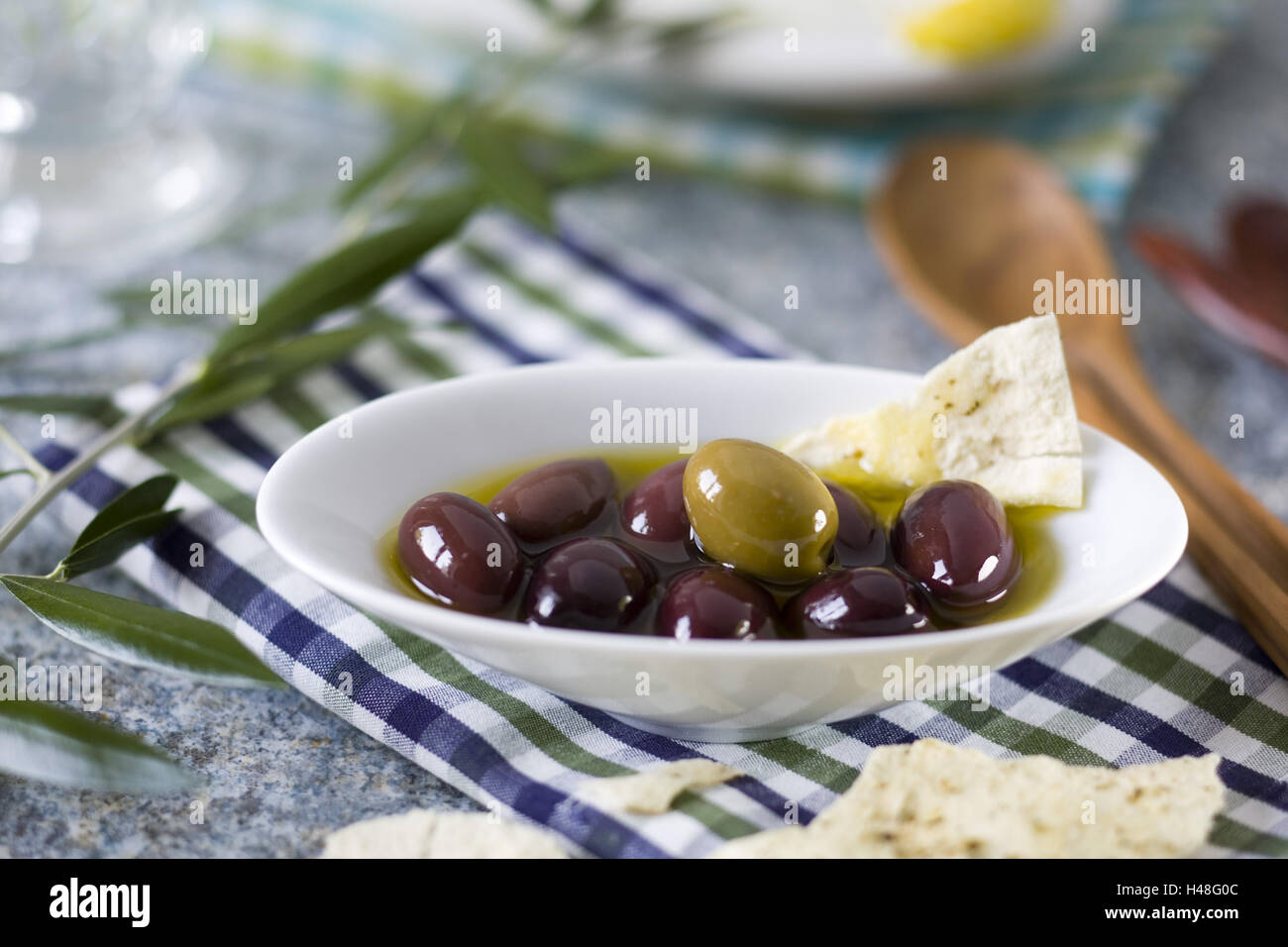 Olive gewölbte Platten auf Blau-Grün-Weiß-Kariertem Stoff, Stockfoto
