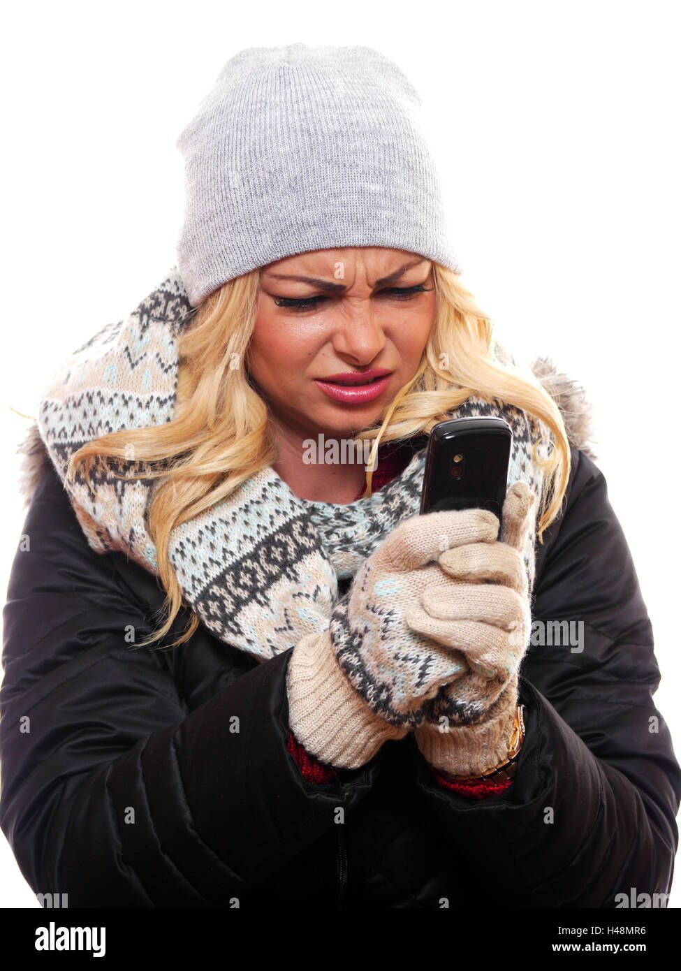 Eine attraktive blonde behaarte Frau ist frustriert versucht, ein Handy zu benutzen. Stockfoto