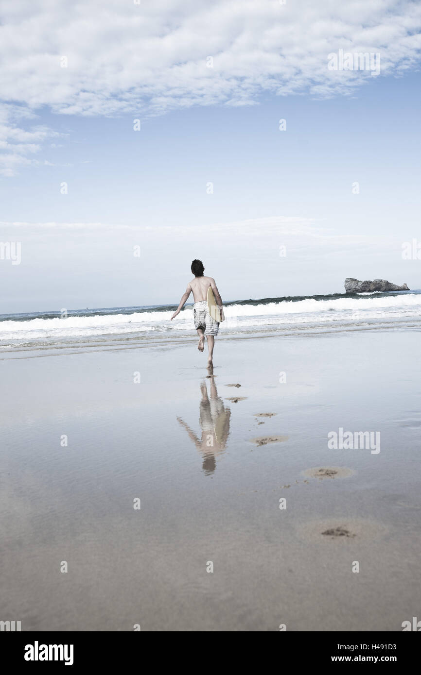 Junge mit Skimboard am Strand, Stockfoto