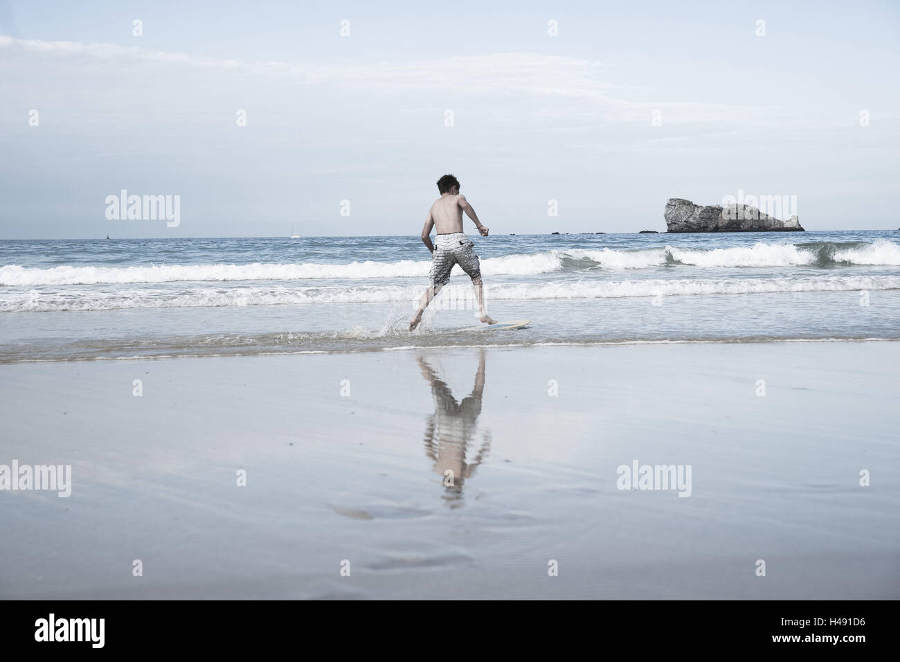 Junge mit Skimboard am Strand, Stockfoto