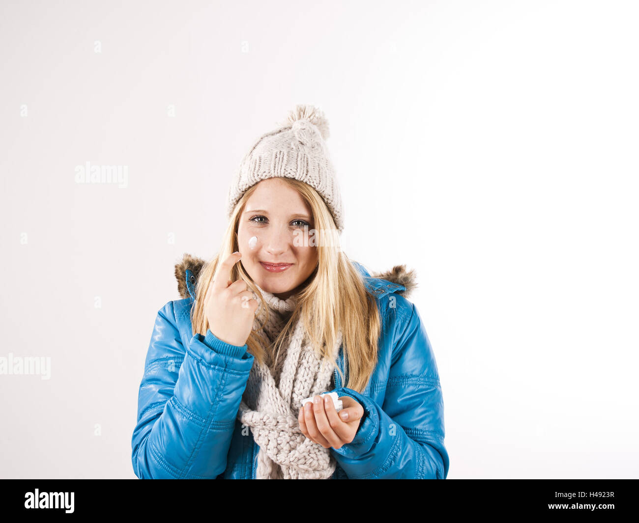 junge Frau mit Wolle Mütze und Schal Cremt sich das Aussehen, Stockfoto