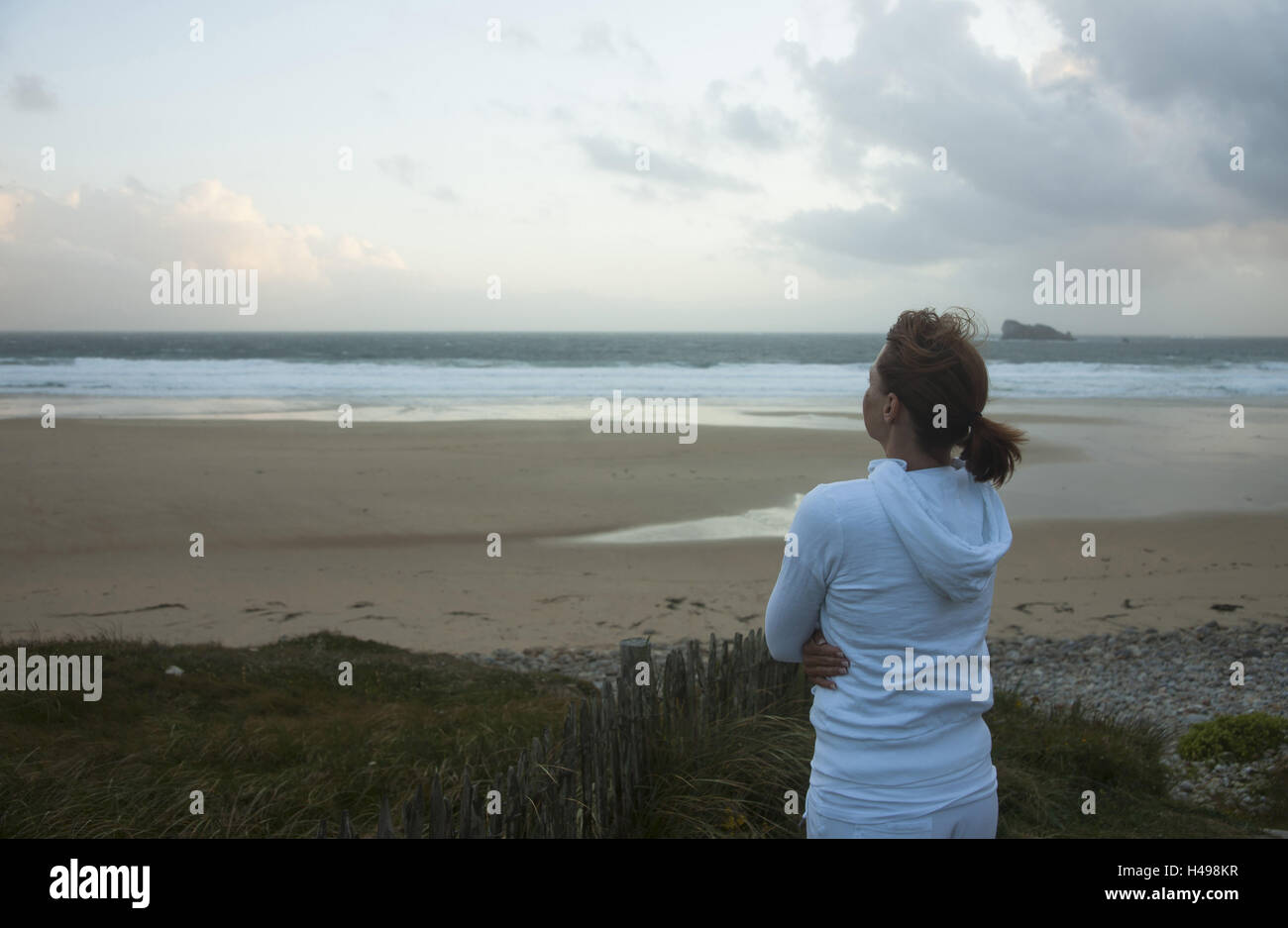 Frau schaut nachdenklich an das Meer, Stockfoto