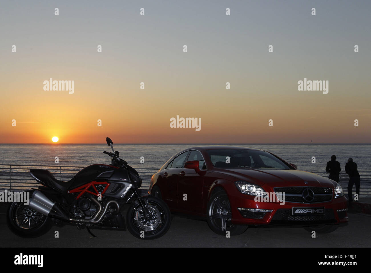Motorrad, Ducati Diavel und Mercedes CLS 63 AMG rot, Musclebike, Sonnenuntergang, Strand, Menschen im Hintergrund, Stockfoto