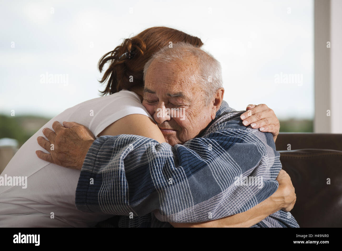 Tochter umarmt und streichelt ihr alten Vater, Stockfoto