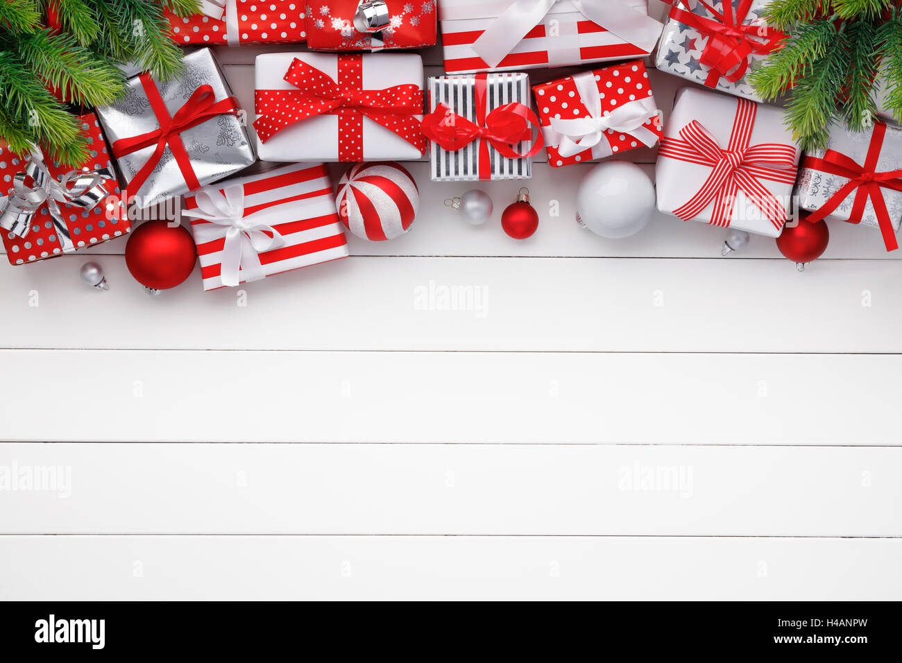 Weihnachtsgeschenke und Kugeln auf weißen Holzbrett Stockfoto