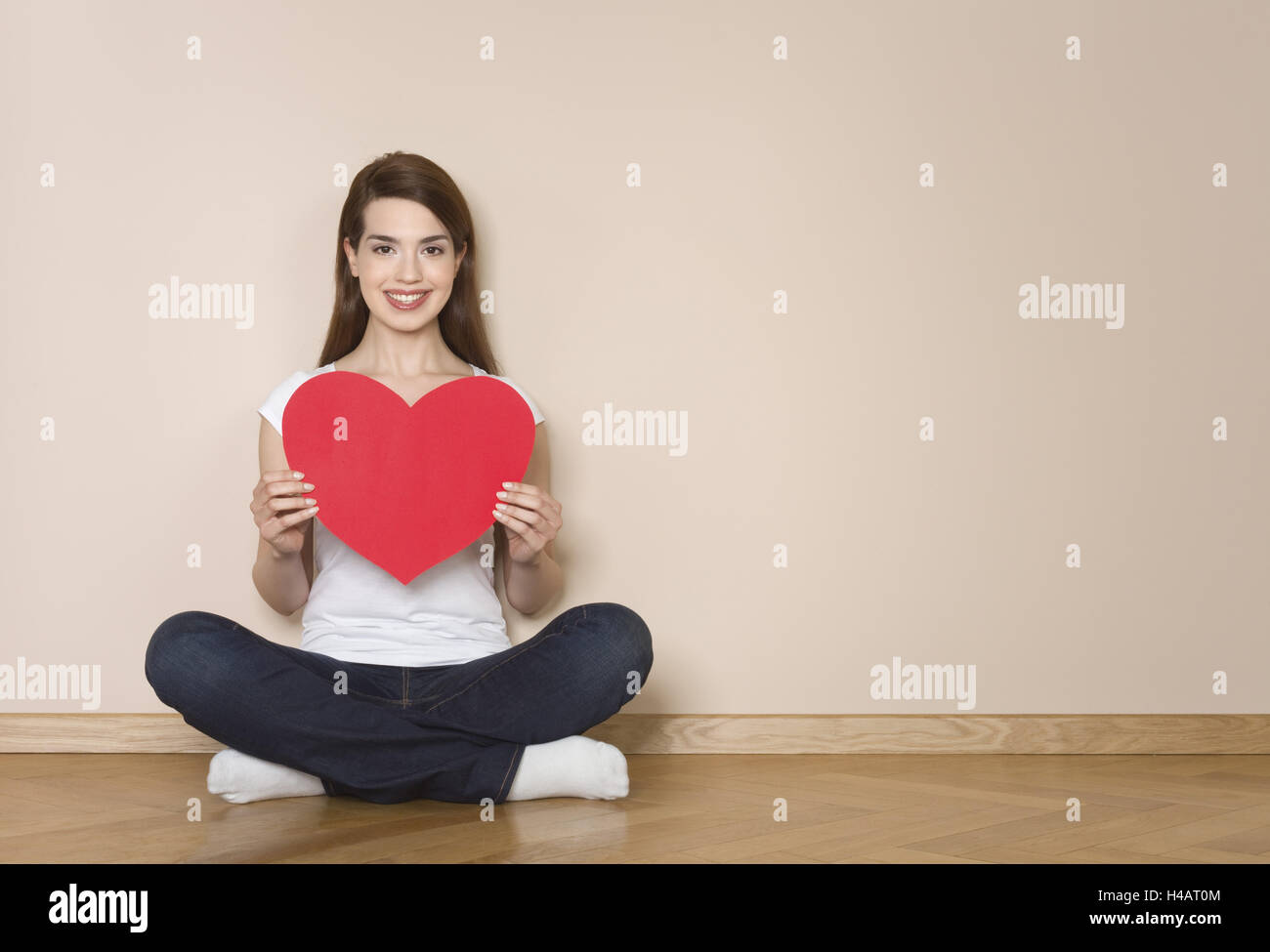 Frau hält großes rotes Herz in ihre Hände, glücklich, Lächeln, Stockfoto