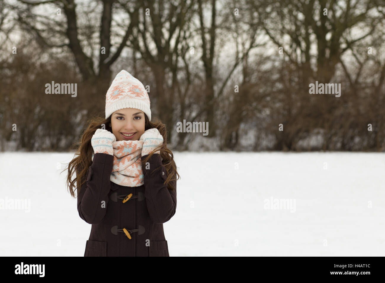 junge Frau im Winter, die Hände auf ihr Kopftuch, Lächeln, gerichtete Kamera, halbe Porträt, Stockfoto