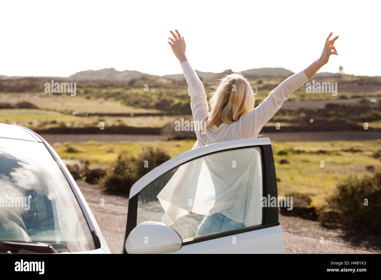 junge Frau aus dem Auto und streckte ihre Arme Stockfoto