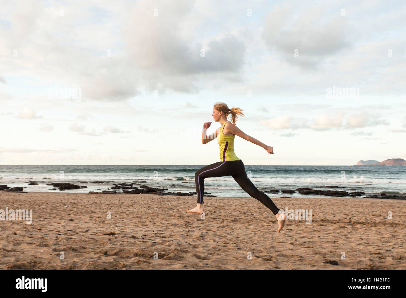 junge Frau tut Sprung am Strand Stockfoto