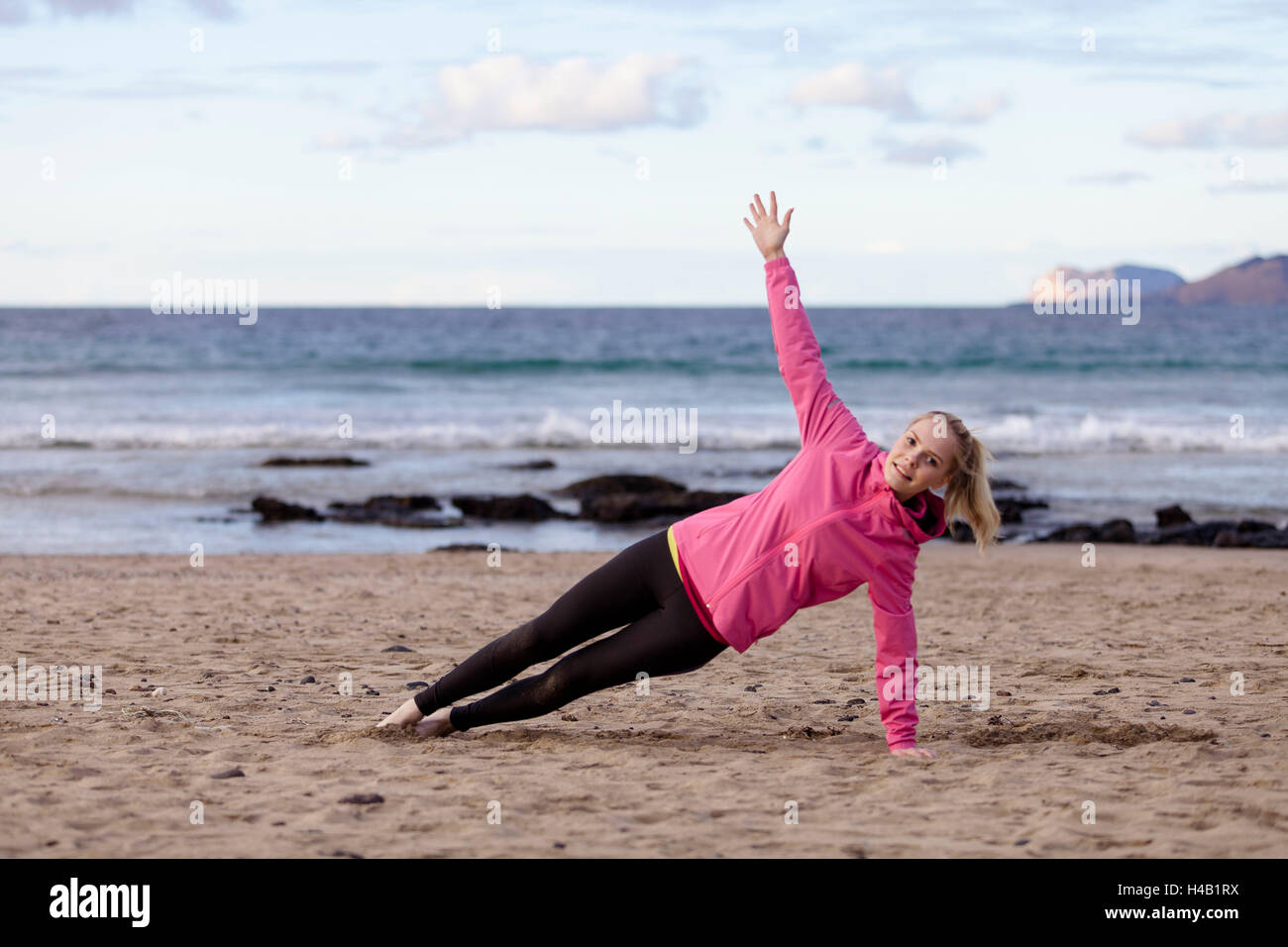 junge Frau macht Yoga und Pilates am Strand - Übung "Board" Stockfoto