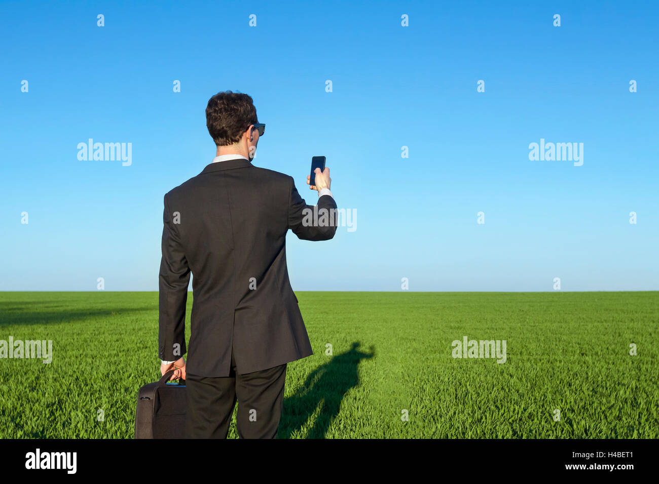 Geschäftsmann mit Smartphone im Feld Stockfoto