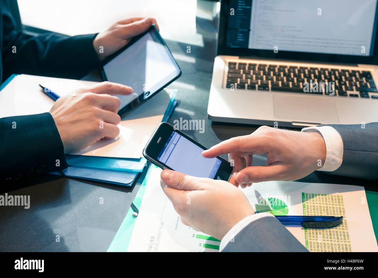 Geschäftsleute in Sitzung präsentiert Charts auf Smartphone, Tablet und Notebook Stockfoto