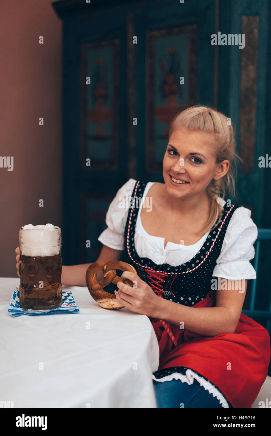 Frau sitzt am Tisch mit Bierkrug und Brezel Stockfoto