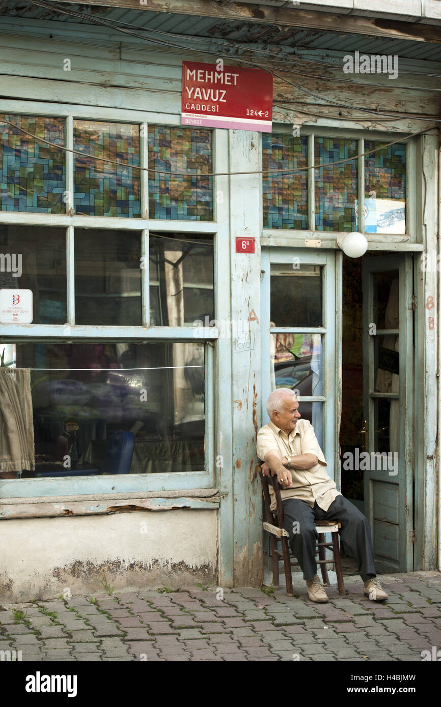 Türkei, Istanbul, Beykoz, Straßenszene, Mann sitzt vor der Unternehmen, Stockfoto