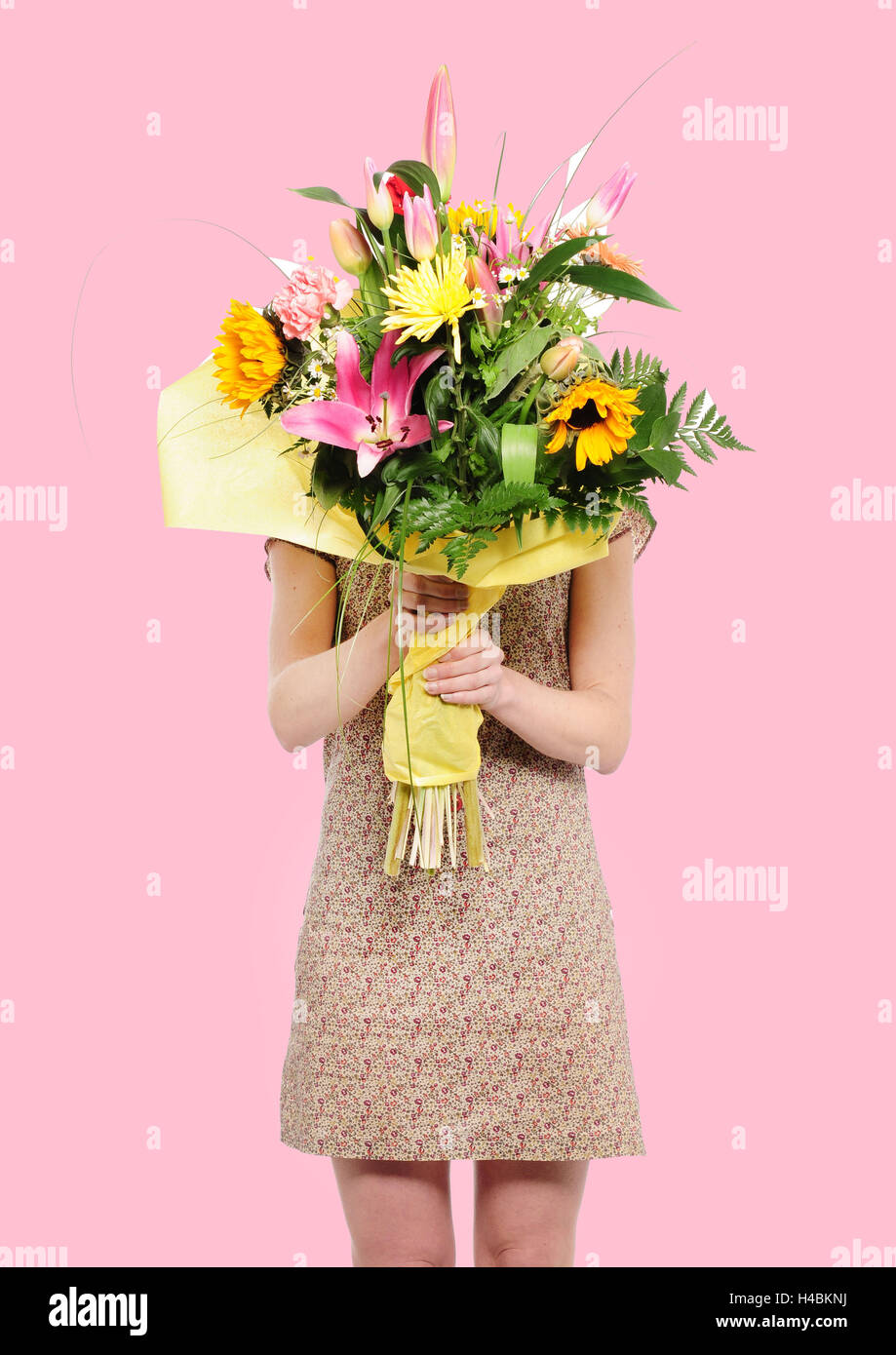 Frau mit Blumenstrauß vor ihr Gesicht, Stockfoto