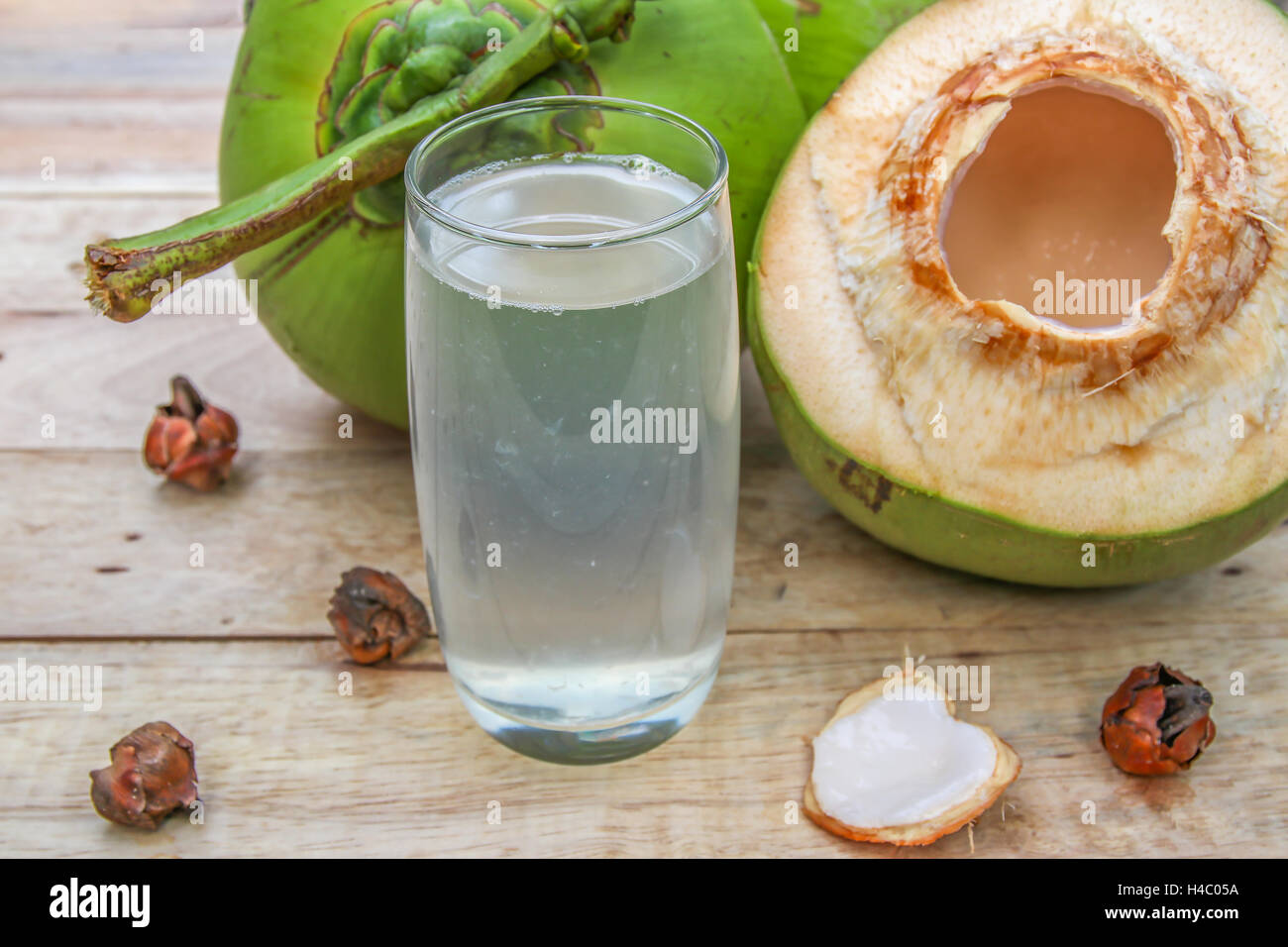 Frische Kokosnuss Wassertrinken aus Glas mit Kokos-Blatt auf hölzernen Hintergrund Stockfoto