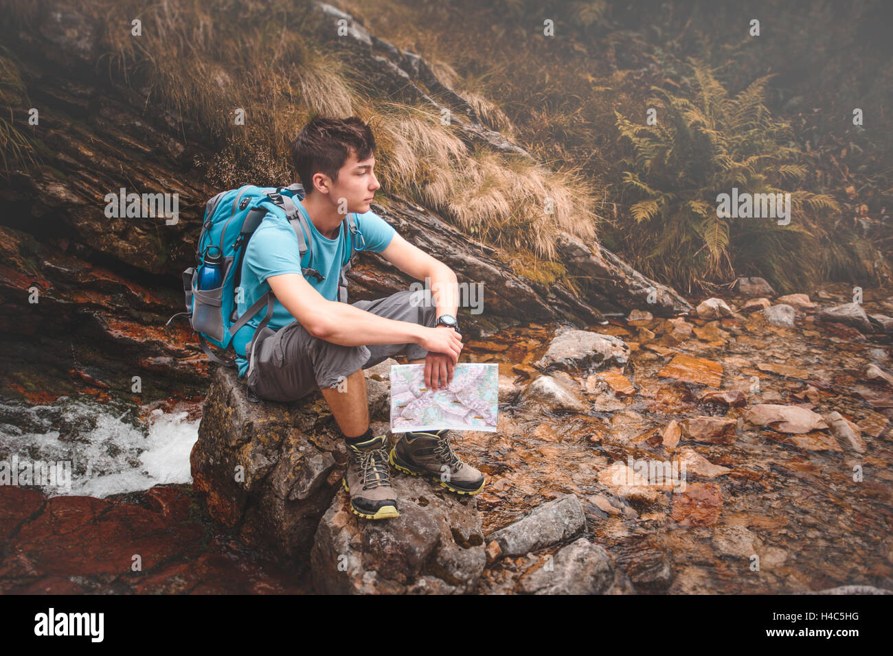 Junge sitzt auf einem Felsen am Bergweg Stockfoto