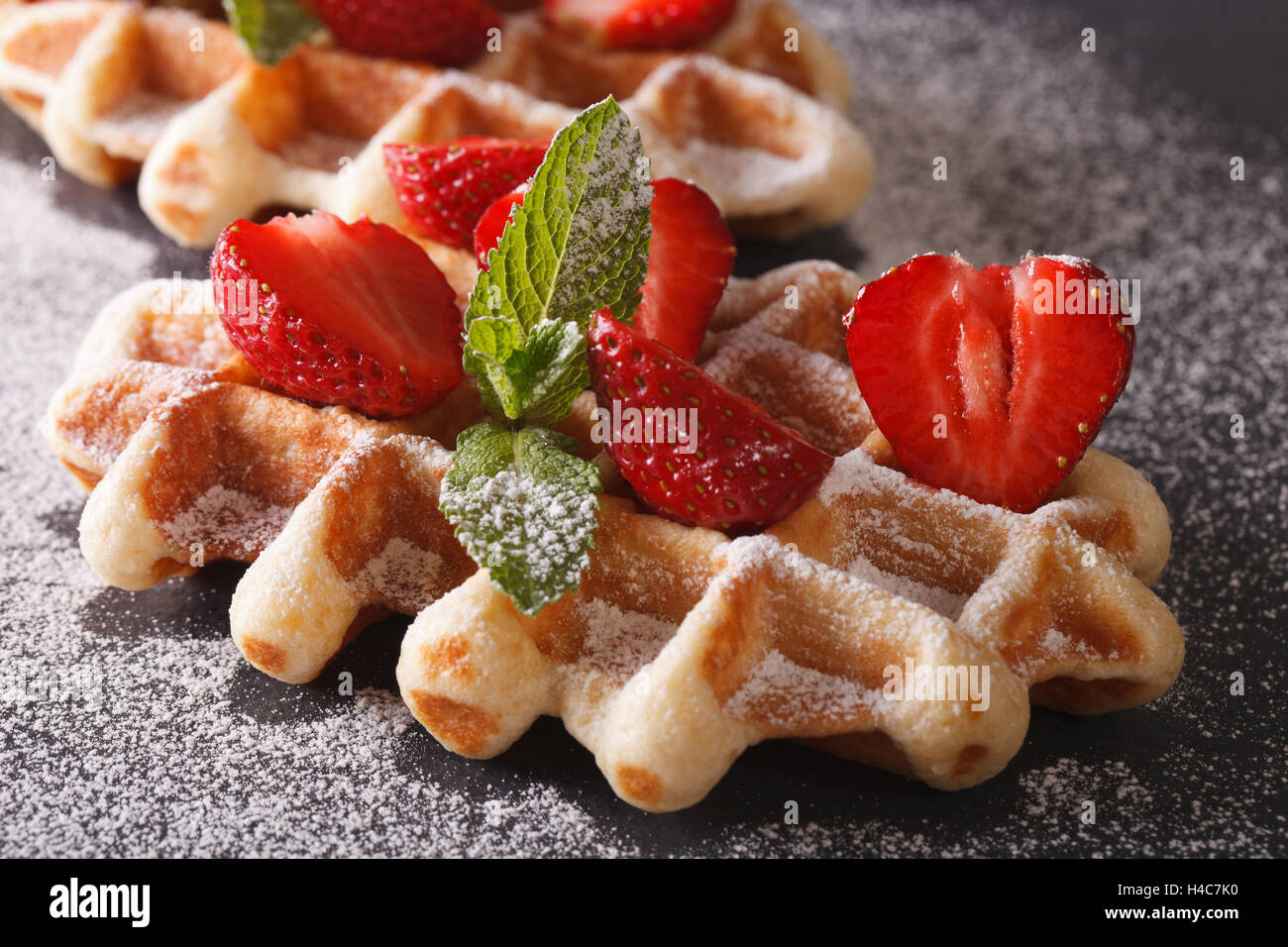 Frisch gebackene Waffeln mit frischen Erdbeeren, bestreut mit Puderzucker Nahaufnahme auf der Schiefertafel. Stockfoto