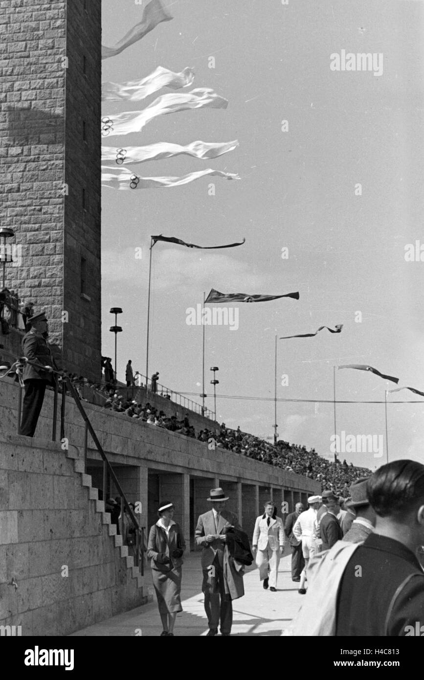 Die Olympischen Und sterben Reichsflaggen Im Wind habe Olympiastadion in Berlin, Deutschland, 1930er Jahre. Olympiasieger und deutsche Fahnen im Wind im Berliner Olympia-Stadion, Deutschland der 1930er Jahre Stockfoto