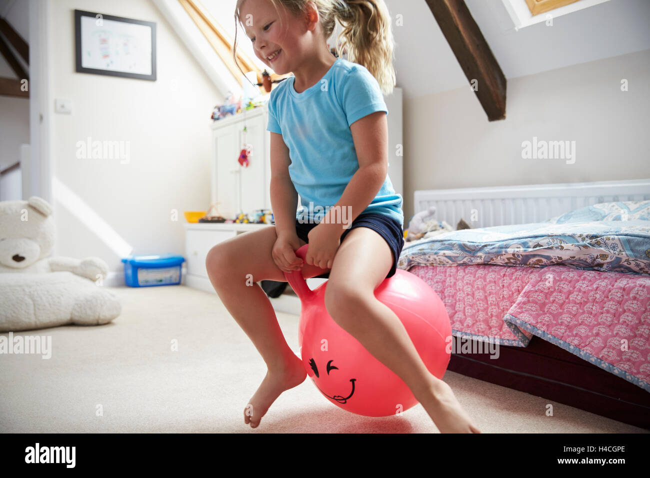 Mädchen springt auf aufblasbaren Ball im Spielzimmer Stockfoto
