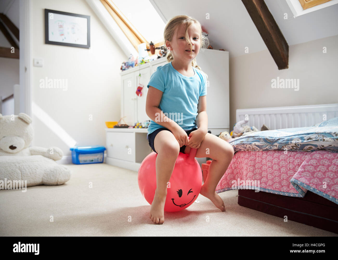 Mädchen springt auf aufblasbaren Ball im Spielzimmer Stockfoto