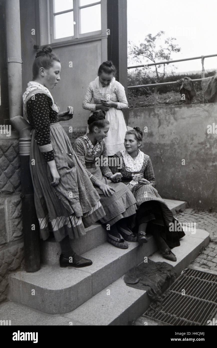 Sterben Sie im Marburger Tracht Gekleideten Jungen Zigarrenrollerinnen Bei der Mittagspause Im Hof Einer Zigarrenfabrik Bei Marburg, Deutschland 1930er Jahre. Junge weibliche Zigarre Rollen tragen eine Marburger Tracht / Kostüm während ihrer Mittagspause im Hof eine Zigarre-Gewebe in der Nähe von Marburg, Deutschland der 1930er Jahre Stockfoto