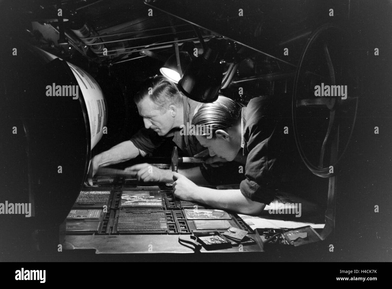 Zwei Drucker Setzen Lettern Zu Einem Schriftstatz ein Einer Rotationsdruckmaschine Zusammen, 1930er Jahre Deutschland. Zwei Drucker arrangieren, dass Metall-Typ auf einer Rotationsdruckmaschine, Deutschland der 1930er Jahre sortiert Stockfoto