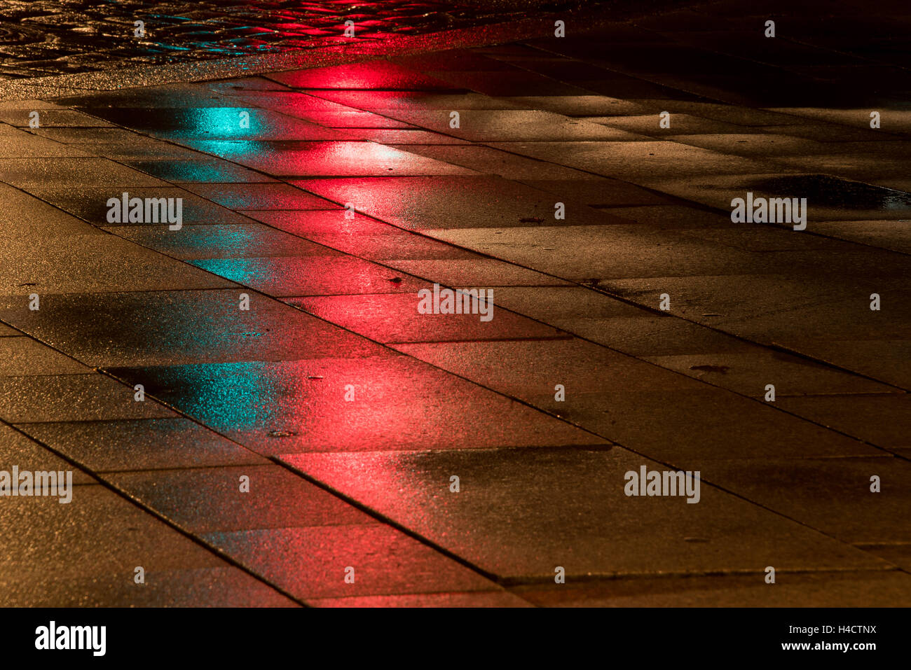 Reflexion der roten und grünen Ampel auf nasser Fahrbahn in der Stadt Stockfoto