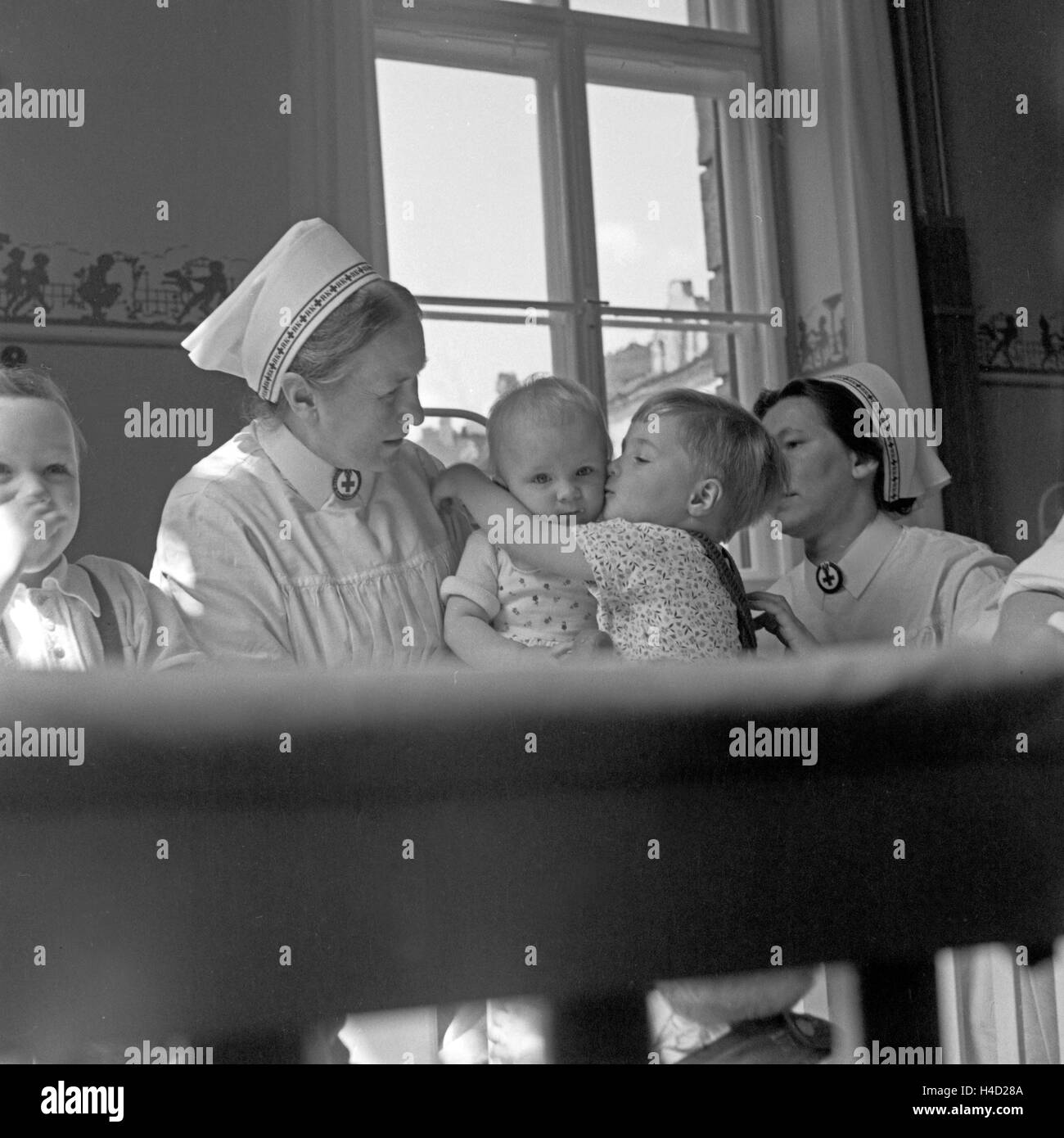 Zwei Schwestern Mit Höhle in der Kinderstation des Rotkreuzkrankenhauses München, 1930er Jahre Deutschland. Zwei Schwestern mit Kindern im Roten Kreuz Krankenhaus Kinder medizinische Abteilung in München der 1930er Jahre. Stockfoto
