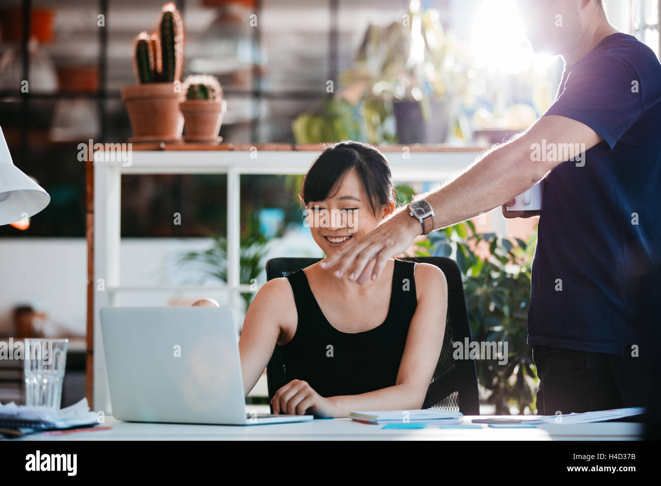 Zwei junge Führungskräfte arbeiten gemeinsam an neuen Geschäftsideen im Amt. Frau sitzt an ihrem Schreibtisch mit Mann zeigte am Laptop. Stockfoto