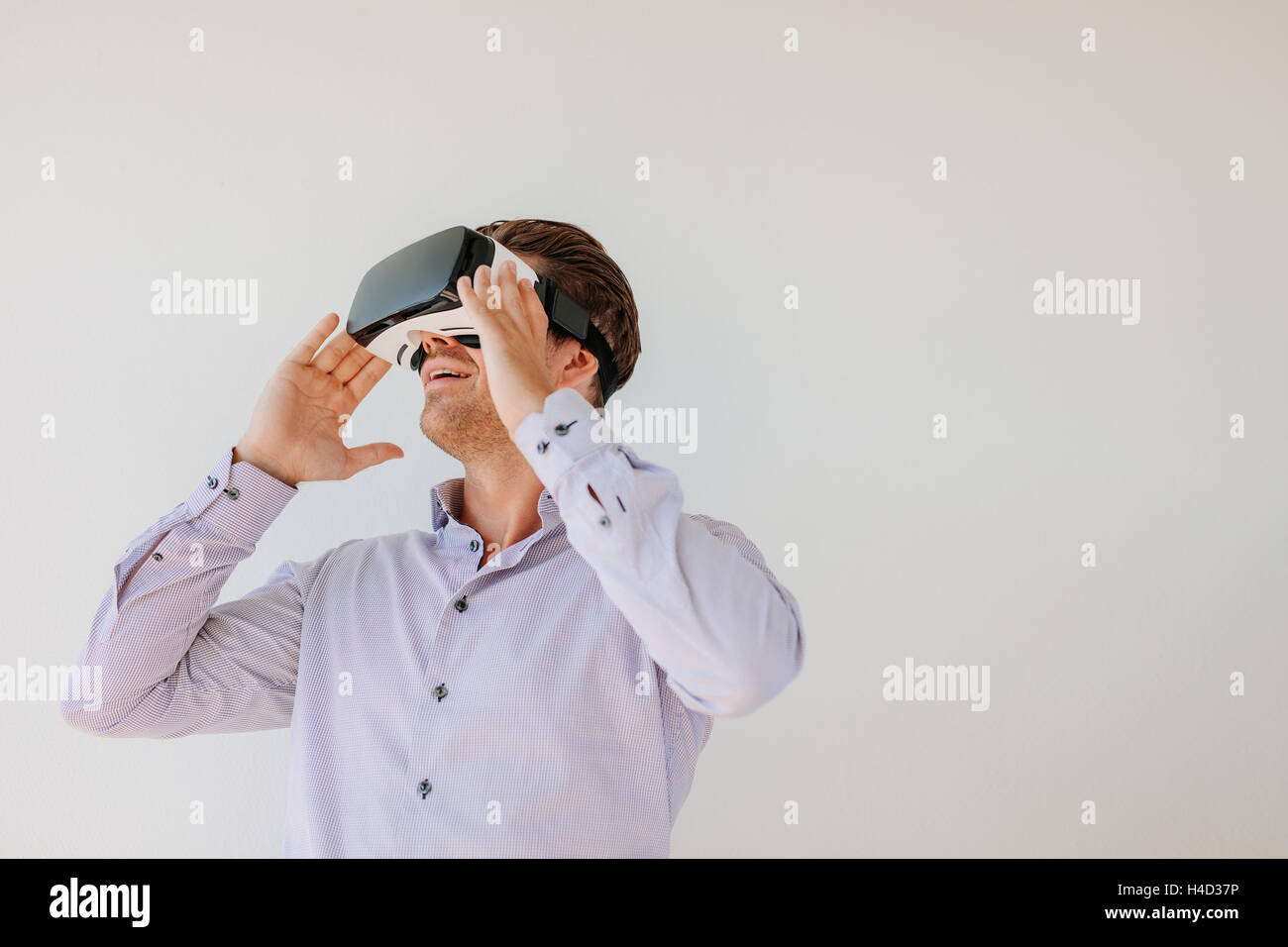 Glücklich Jüngling mit textfreiraum die virtual-Reality-Kopfhörer vor grauem Hintergrund. Kaukasische Männermodel tragen VR goggl Stockfoto
