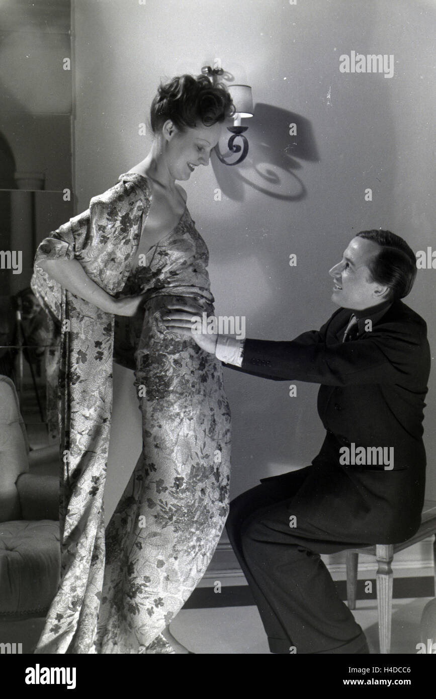 Der Modeschöpfer Heinz Schulze-Bibernell Und Ein Modell Bei der Anprobe Eines Kleides, Deutschland ca. 1939. Der Modeschöpfer Heinz Schulze-Bibernell und ein Modell, das versucht, ein Kleid, Deutschland ca. 1939. Stockfoto
