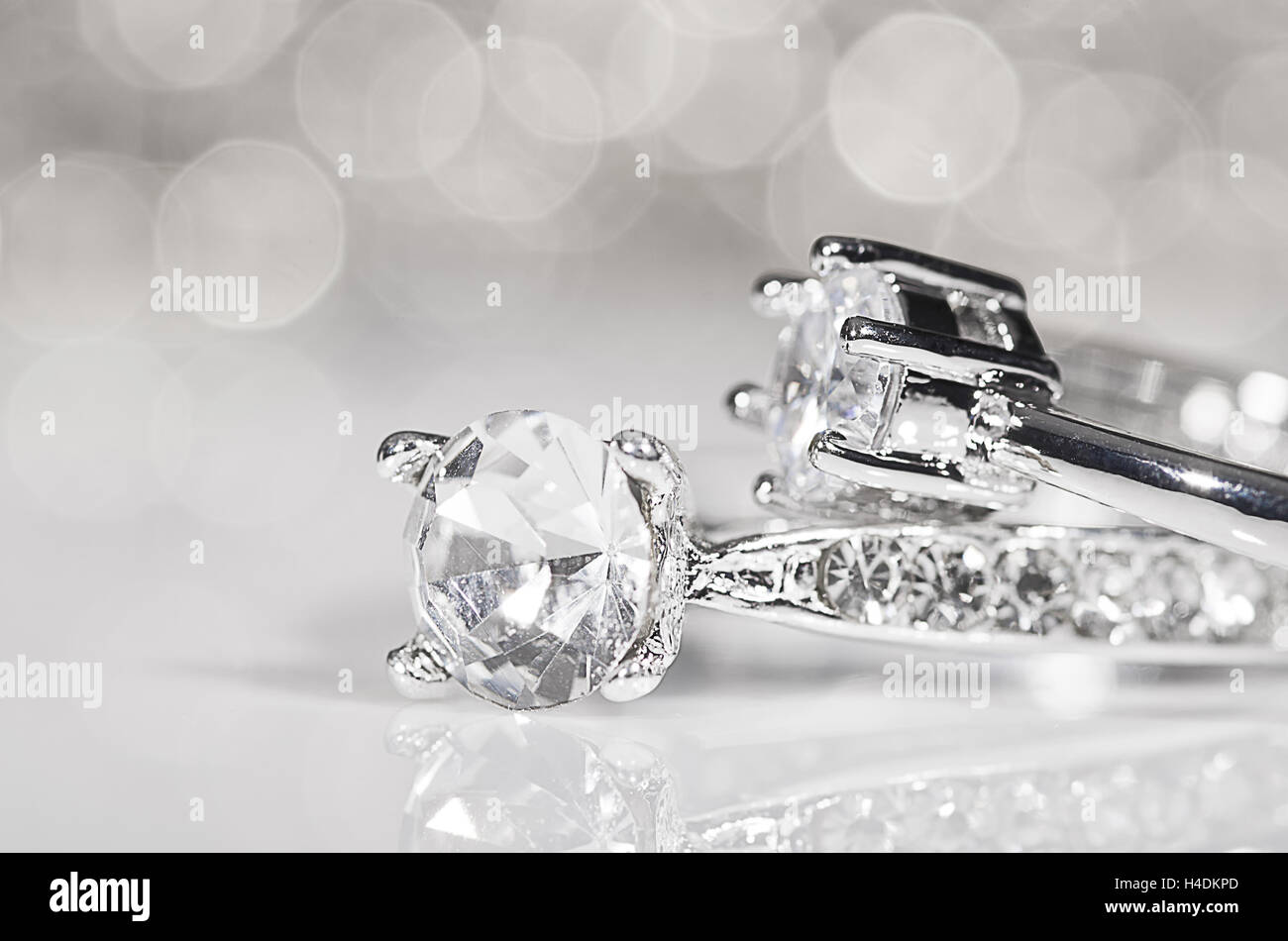 Silber Ringe mit Diamanten auf die weiße Fläche mit Reflexionen in den Hintergrund. Stockfoto