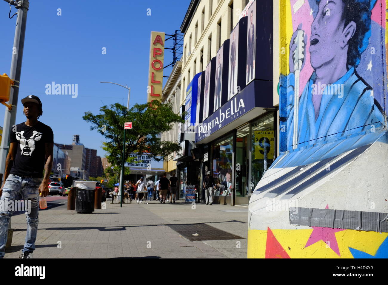 Fußgänger an der 125th Street mit dem Zeichen des Apollo Theater im Hintergrund. Harlem, New York City, USA Stockfoto