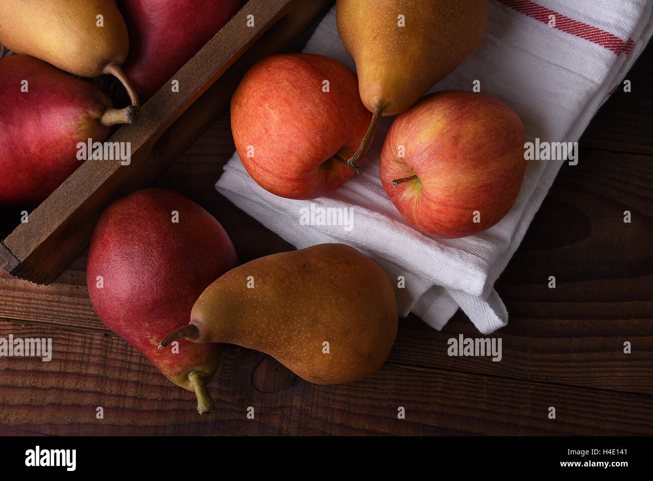 Frisch gepflückt Birnen und Äpfel in einer hölzernen Kiste und Handtuch auf einem rustikalen Holztisch. Ansicht von oben im Querformat. Stockfoto