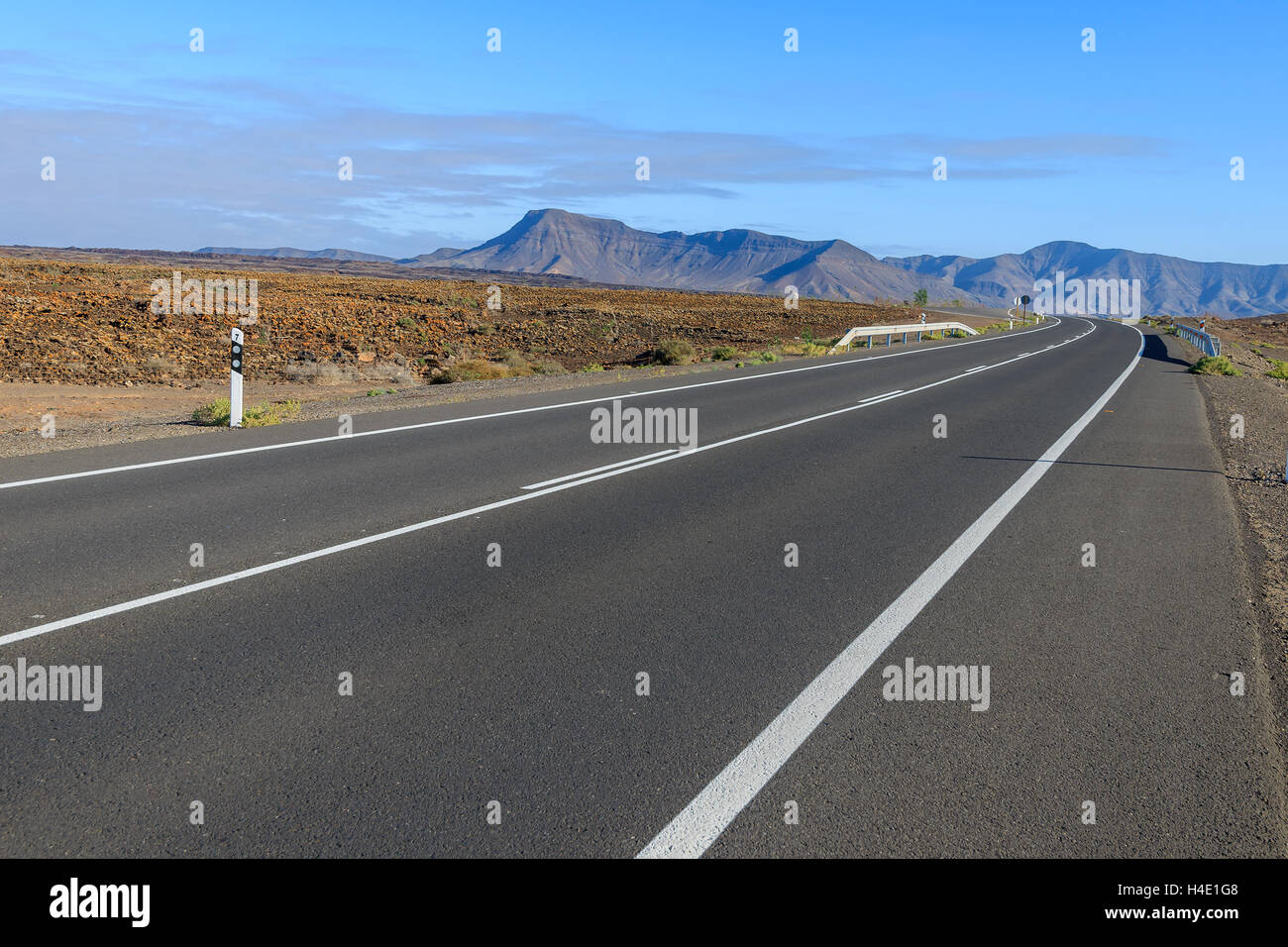 Straße in der Wüstenlandschaft und vulkanischen Bergen im Hintergrund, Fuerteventura, Kanarische Inseln, Spanien Stockfoto