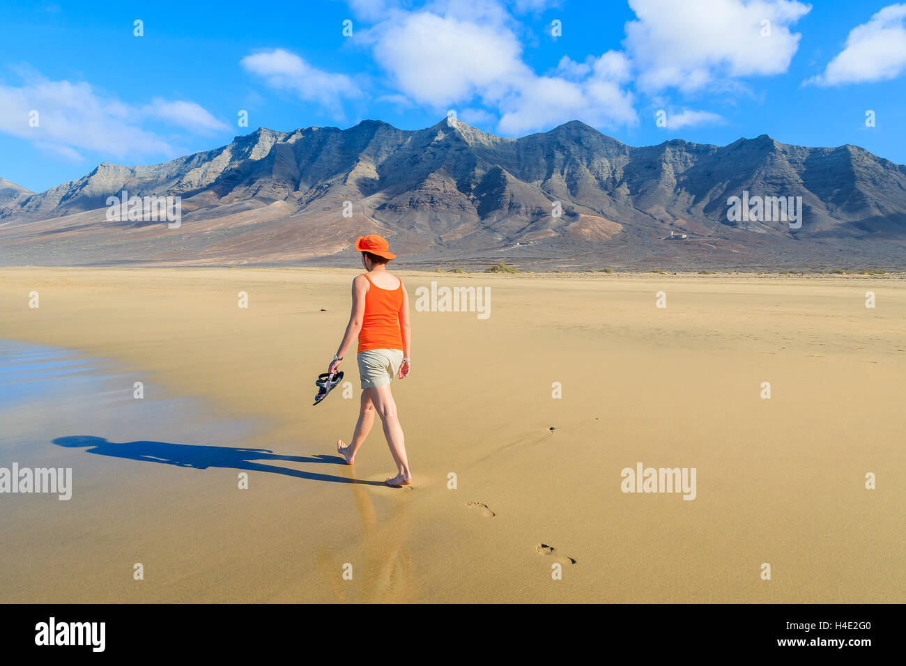 Junge Frau Touristen zu Fuß am Strand von Cofete und vulkanischen Bergen im Hintergrund auf Jandia Peninsula, Fuerteventura, Kanarische Inseln, Spanien Stockfoto