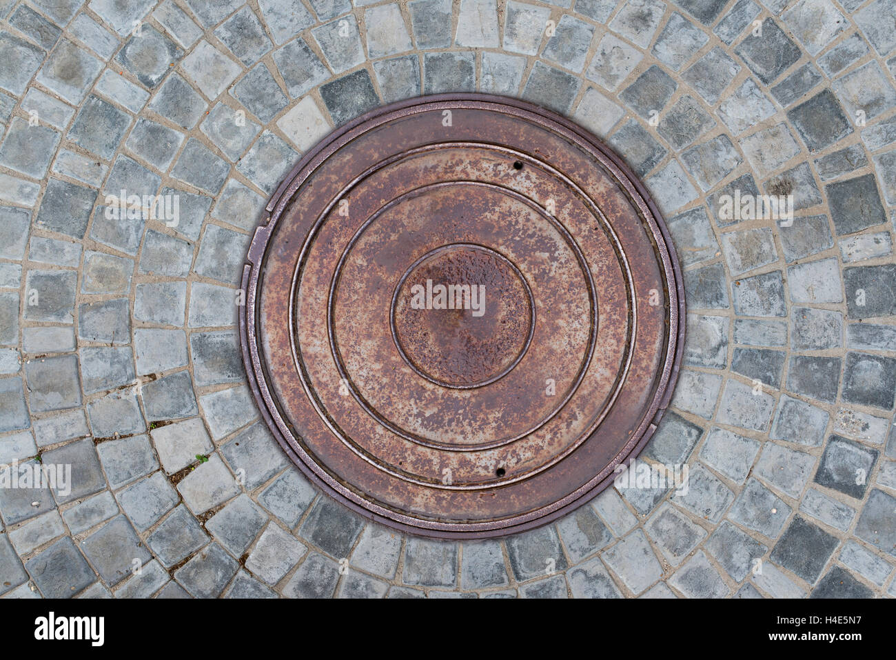 Nahaufnahme Foto von Rost alte Kanalisation Kanaldeckel auf der städtischen Asphaltstraße. Regen-Szene. Stockfoto
