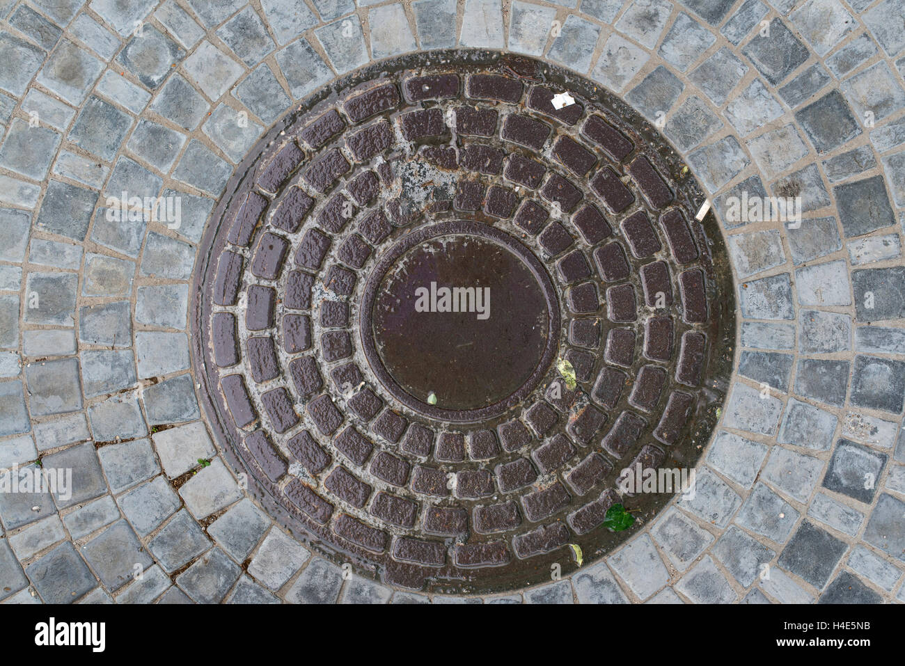 Nahaufnahme Foto von Rost alte Kanalisation Kanaldeckel auf der städtischen Asphaltstraße. Regen-Szene. Stockfoto