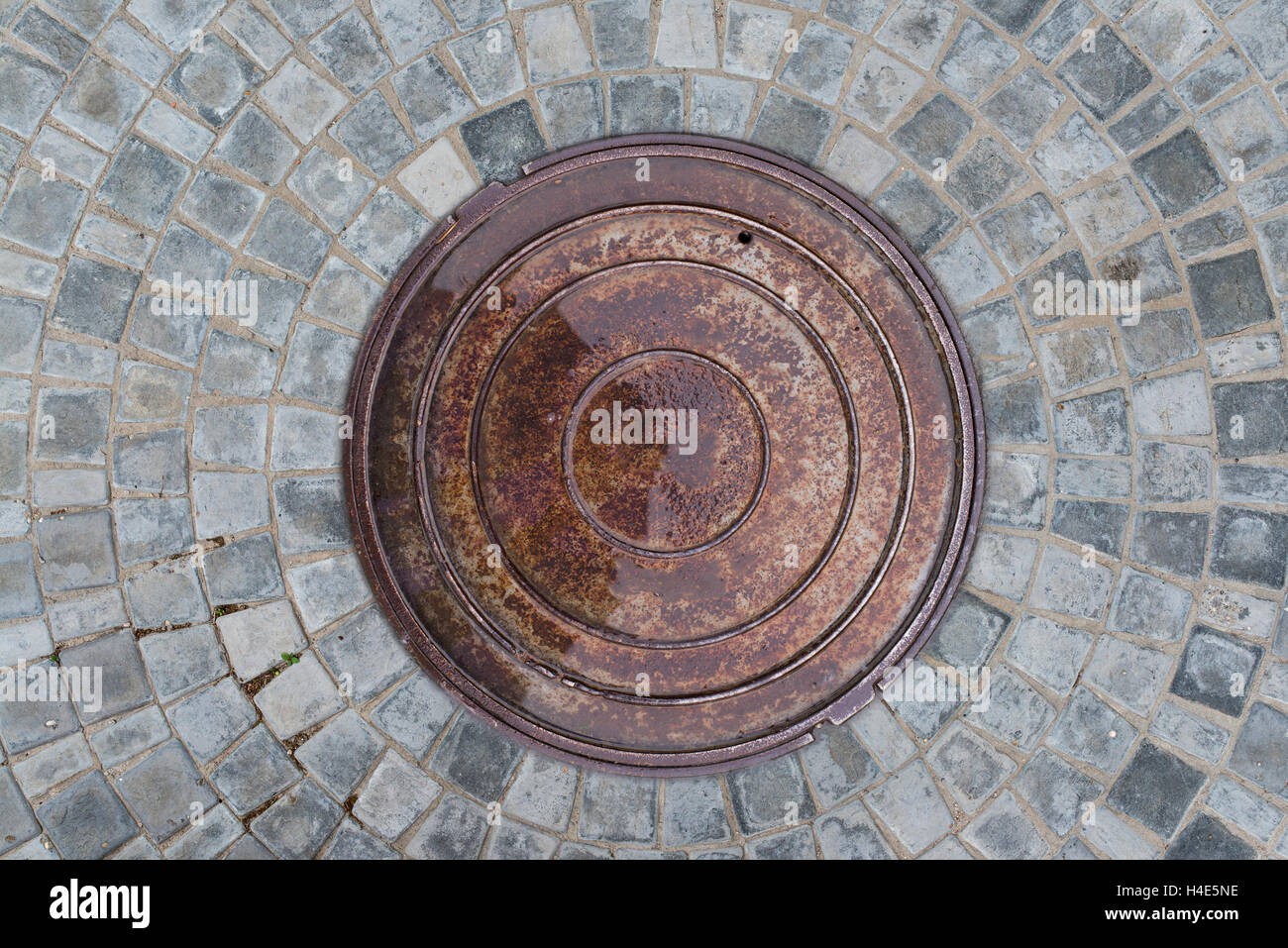 Nahaufnahme Foto von Rost alte Kanalisation Kanaldeckel auf der städtischen Asphaltstraße. Regen-Szene. Stockfoto
