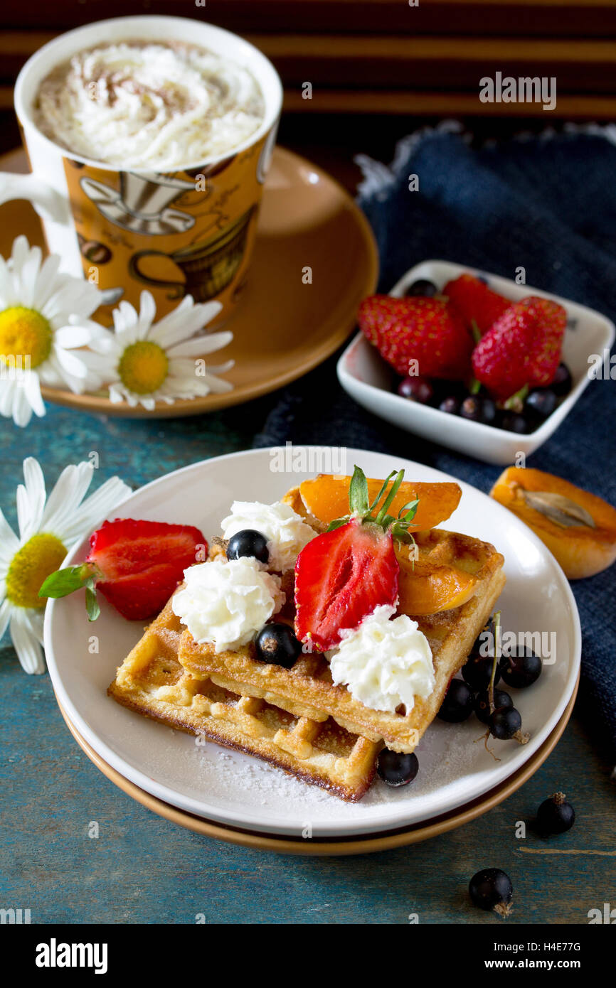 Traditionelle belgische Waffeln mit Sahne Schlagsahne Sahne und frische Beeren auf Vintage-Hintergrund, zum Frühstück serviert. Stockfoto
