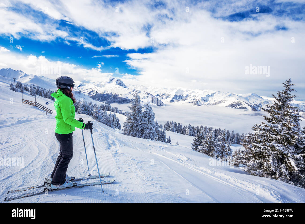 Junge Frau Skifahren im Skigebiet Kitzbühel und genießen das schöne Wetter mit blauem Himmel und Alpen in Österreich. Stockfoto