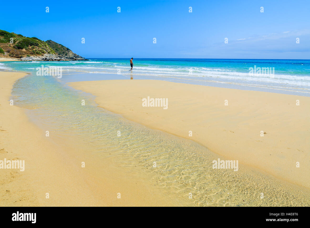 Unbekannter Mann zu Fuß auf den goldenen Sandstrand der Cala Sinzias und türkisfarbenes Meerwasser, Insel Sardinien, Italien Stockfoto