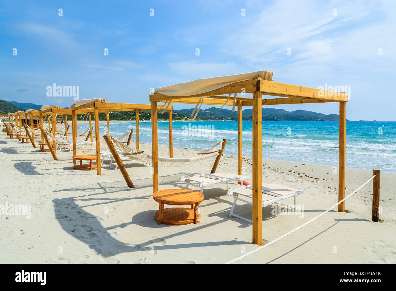 Liegestühle und Hängematten mit Teak Holztisch am weißen Sandstrand in Porto Giunco Bucht, Insel Sardinien, Italien Stockfoto