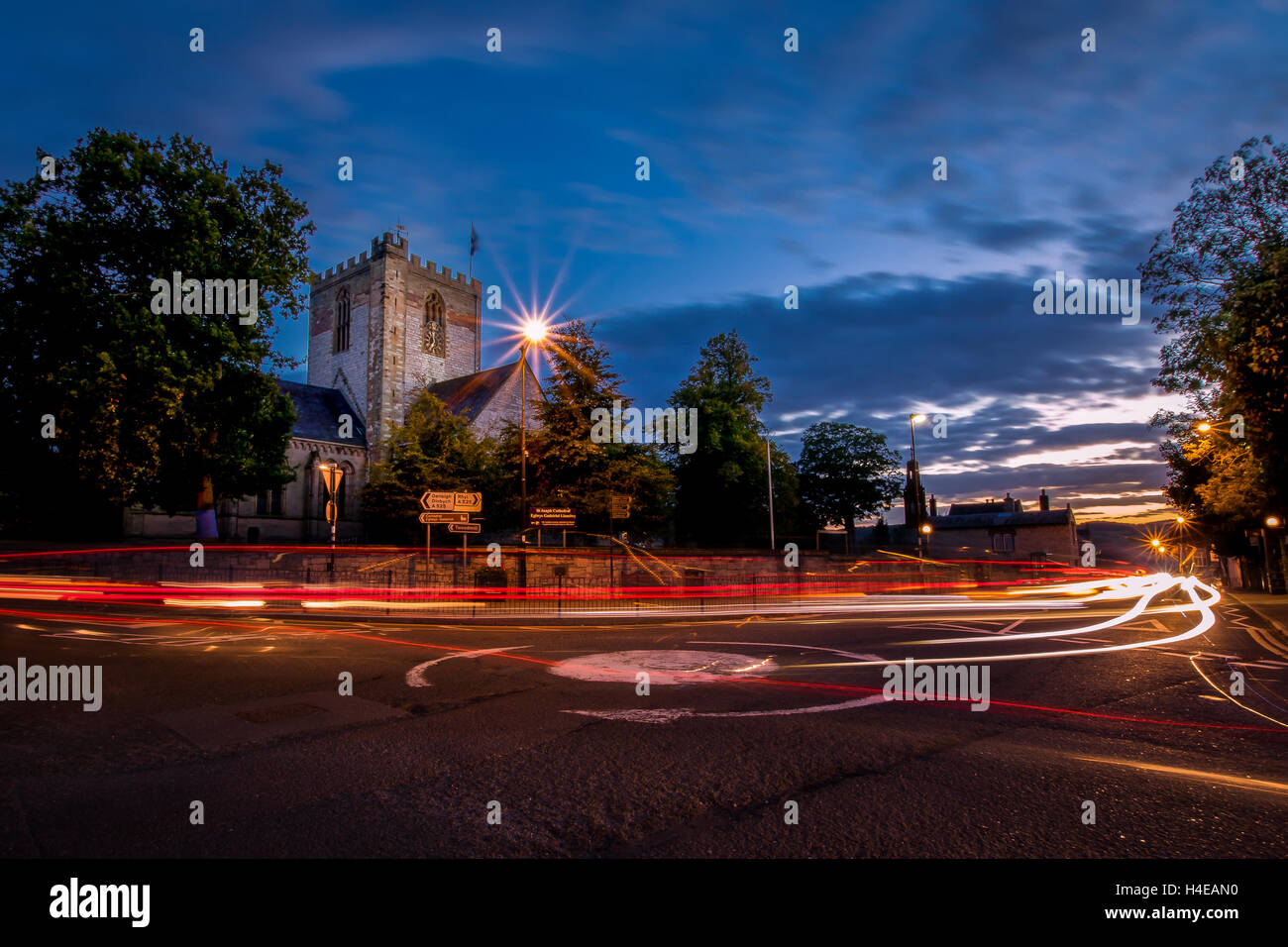 Verkehr geht durch St.Asaph Kathedrale in Nord-Wales kurz nach Sonnenuntergang an einem Herbstabend. Stockfoto