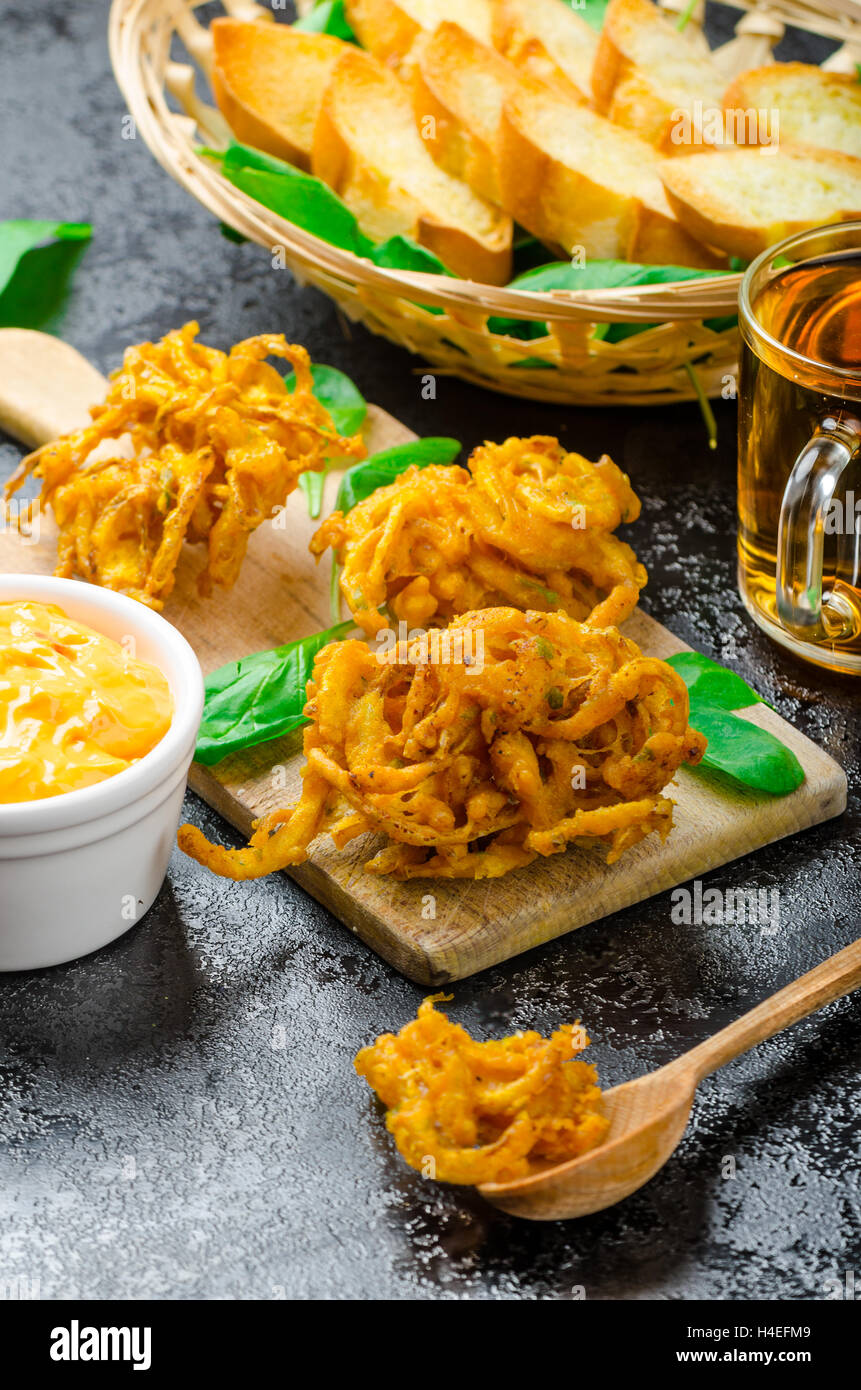 Knusprige Zwiebel-Bhajis mit Creame Käse dip mit Jalapeno und Crunchi Toast auf Blattspinat und tschechisches Bier Stockfoto