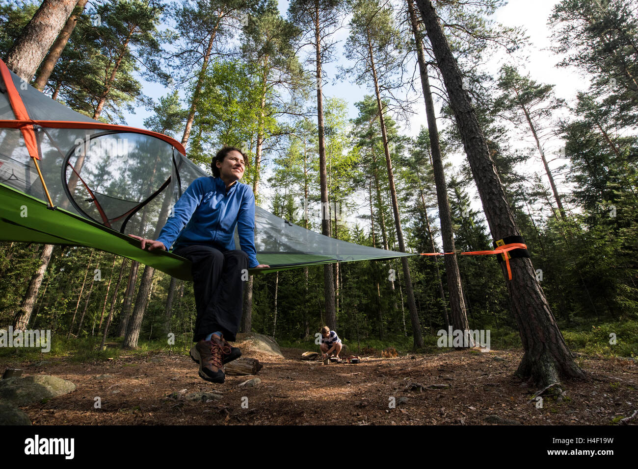 Junge Frau sitzt auf einem Tentsile Baum Zelt, Nuuksio Nationalpark, Helsinki, Finnland Stockfoto