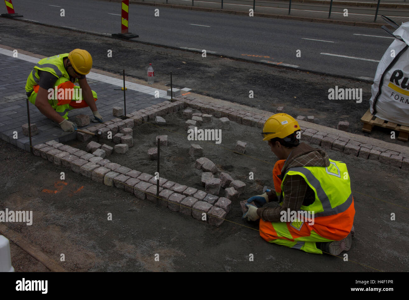 Arbeiter reparieren eine traditionelle Kopfsteinpflaster in Helsinki, Finnland. Stockfoto