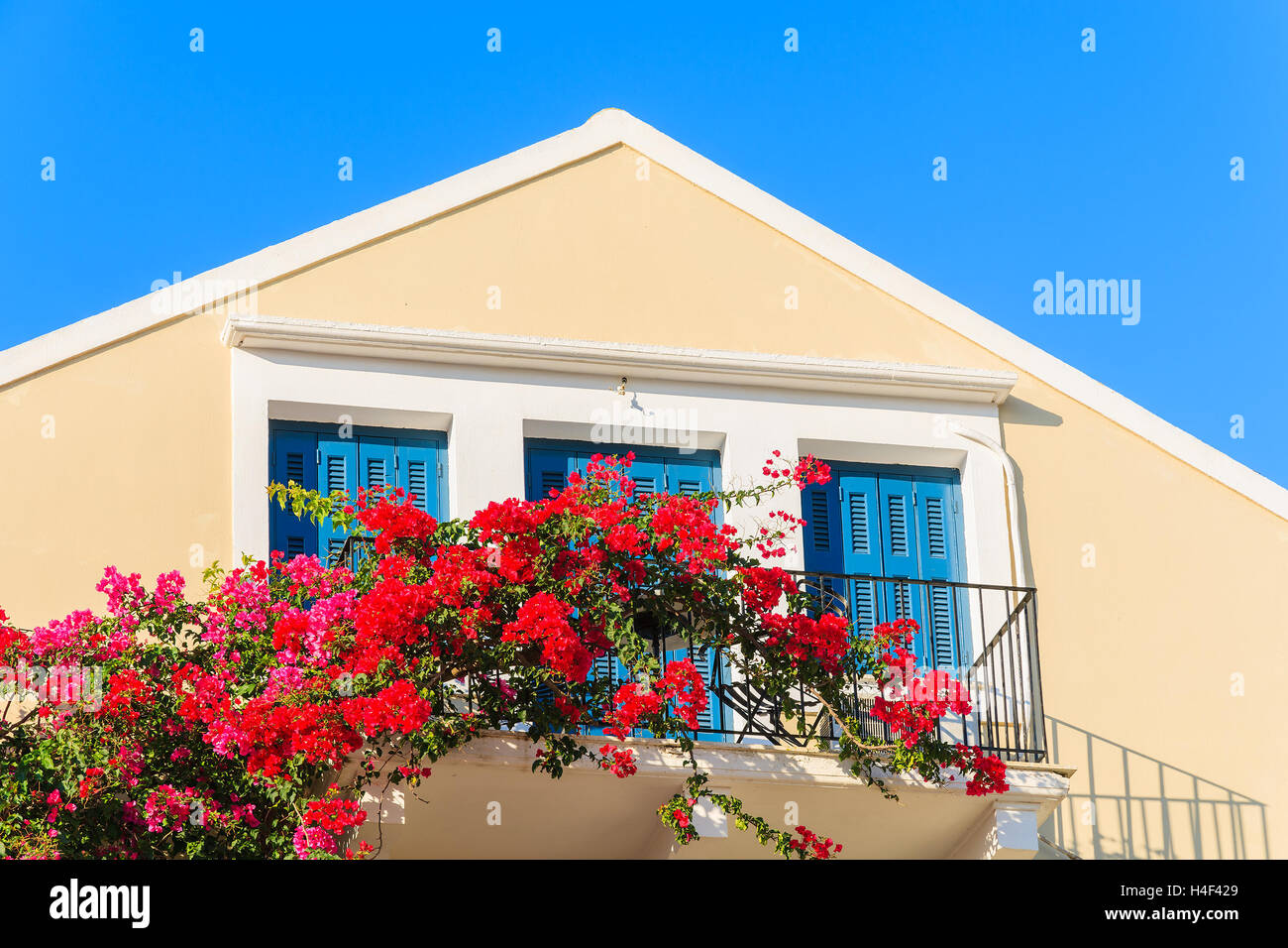 Rote Bougainvillea Blumen auf Balkon des typisch griechisches Haus in der Stadt Fiskardo Kefalonia Island, Griechenland Stockfoto