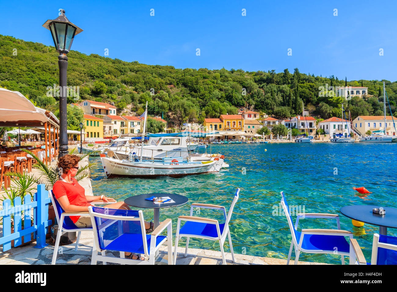 KIONI Hafen, Insel ITHAKA - SEP 19, 2014: junge Frau Touristen sitzen am Tisch im Restaurant im Hafen Kioni. Griechische Inseln sind popul Stockfoto